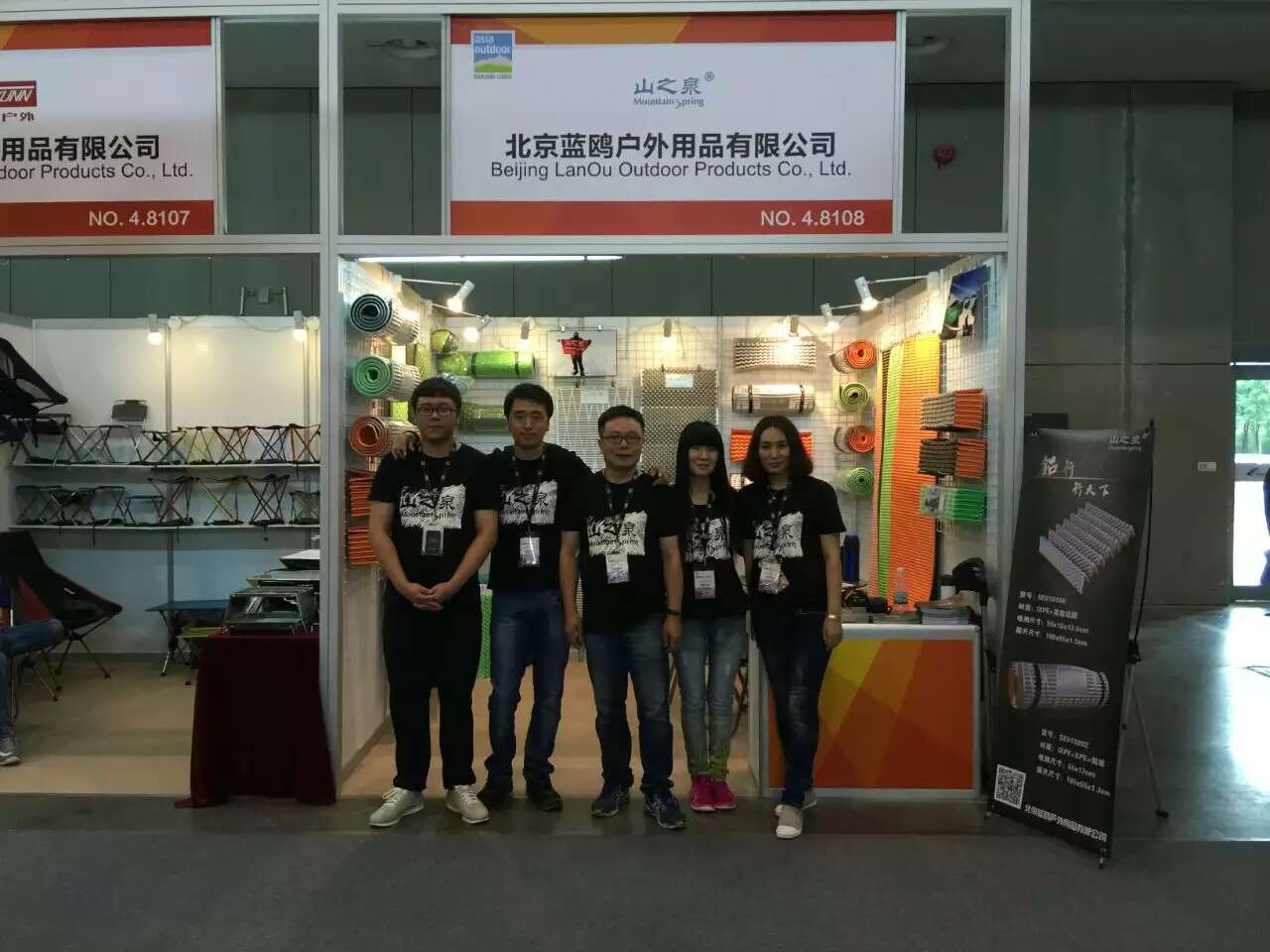 Five people posed for a photo in front of the Mountain Spring booth, including the founders. Many foam pads were displayed on the booth walls.
