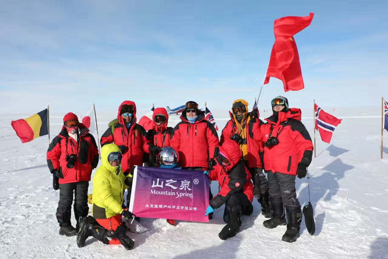 Eight people dressed in red professional outdoor gear posed for a group photo in the snow. One of them held up the Chinese national flag, while the two in the middle half-squatted down and unfurled a flag bearing the Mountain Spring logo.